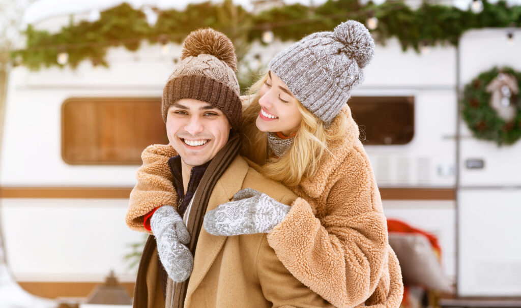 how to winterize your rv - couple in winter clothes in front of trailer