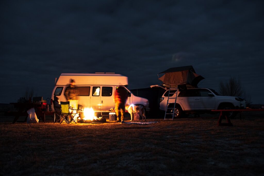 Nightime setting with a camper van and people outside of it